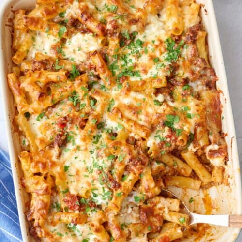 Baked ziti in the baking dish garnished with chopped parsley.