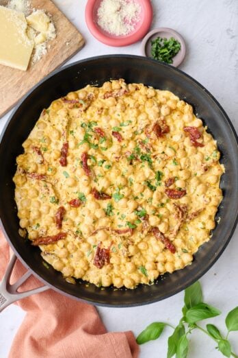 Marry me chickpeas in the skillet garnished with chopped basil with small dishes of extra sun-dried tomatoes, parmesan and basil nearby.