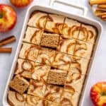Applesauce cake in the baking dish topped with cream cheese frosting with apple butter swirl, cut into 24 pieces with a few pieces propped up to see inside.