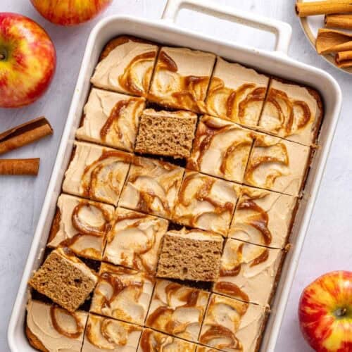 Applesauce cake in the baking dish topped with cream cheese frosting with apple butter swirl, cut into 24 pieces with a few pieces propped up to see inside.