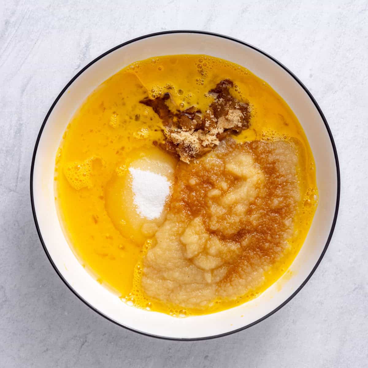 Whisked eggs in a large bowl with both sugars, oil, applesauce and vanilla added before combining.