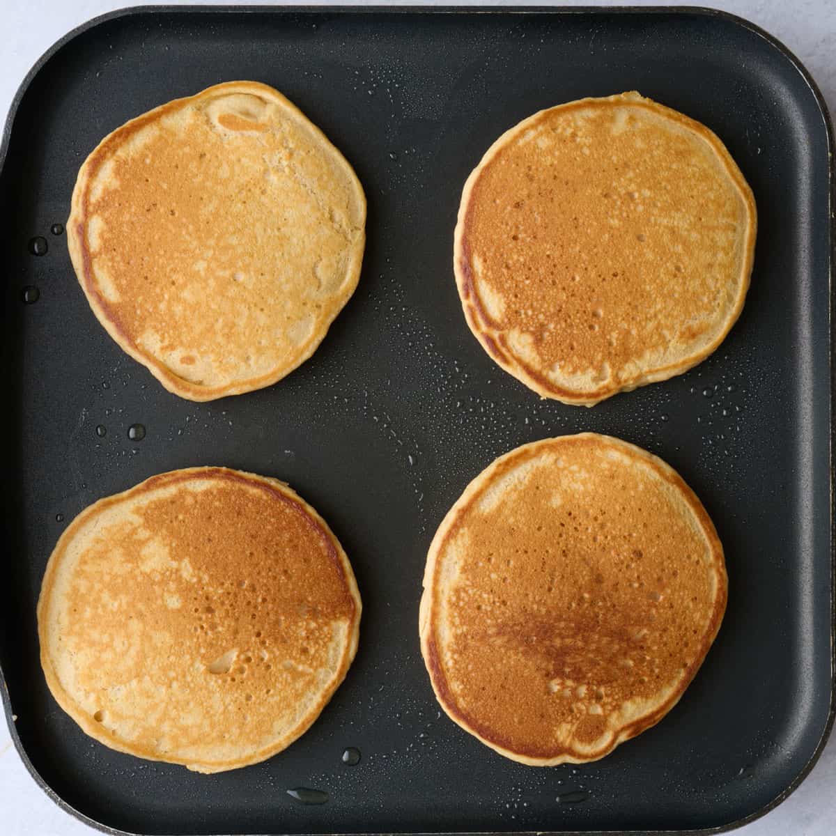 Four pancakes on a square pan after flipping.